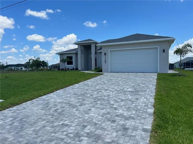 View of front facade featuring a garage and a front lawn