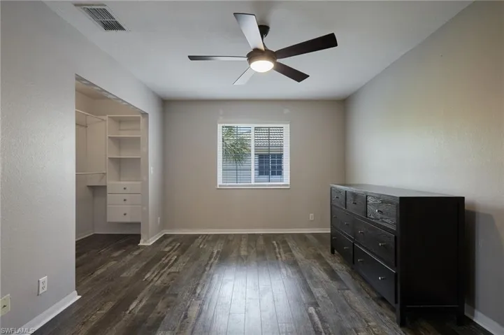 Bedroom featuring ceiling fan, baseboards, visible vents, and dark wood finished floors