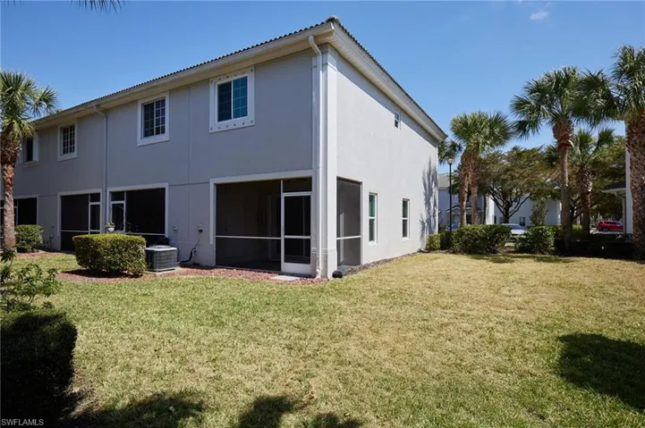 Rear view of house featuring a sunroom, central AC unit, a lawn, and stucco siding