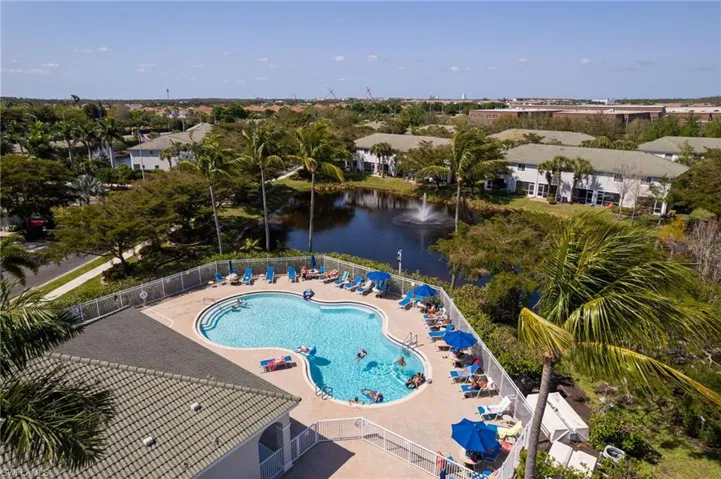 Community pool featuring a patio area, a water view, and fence