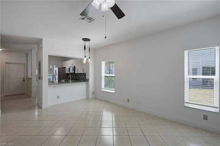 Spare room with ceiling fan, visible vents, baseboards, and light tile patterned flooring