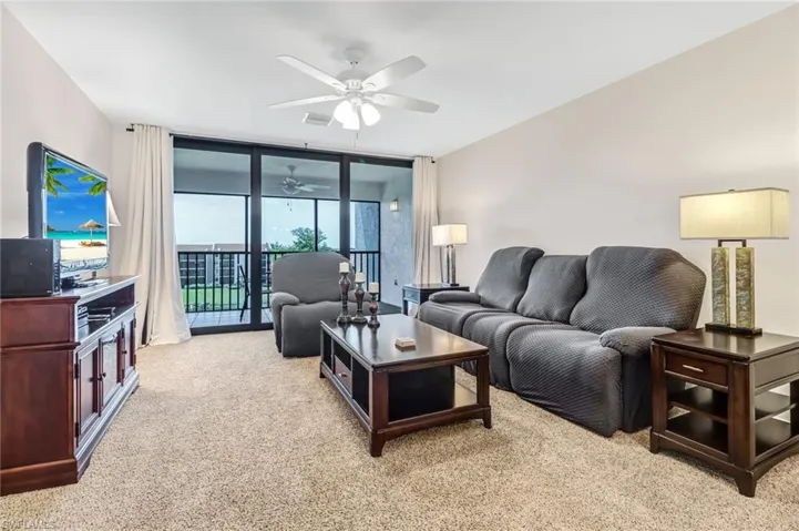 Carpeted living room featuring floor to ceiling windows and ceiling fan