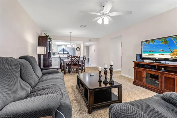 Carpeted living room featuring ceiling fan with notable chandelier