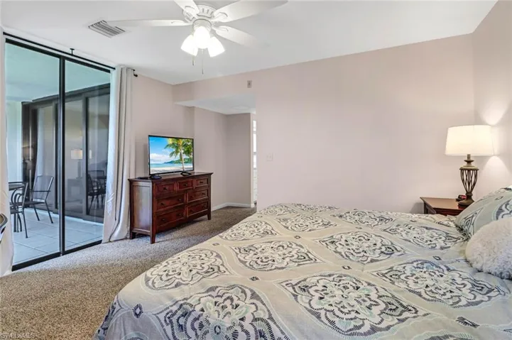 Carpeted bedroom with access to exterior, ceiling fan, and expansive windows