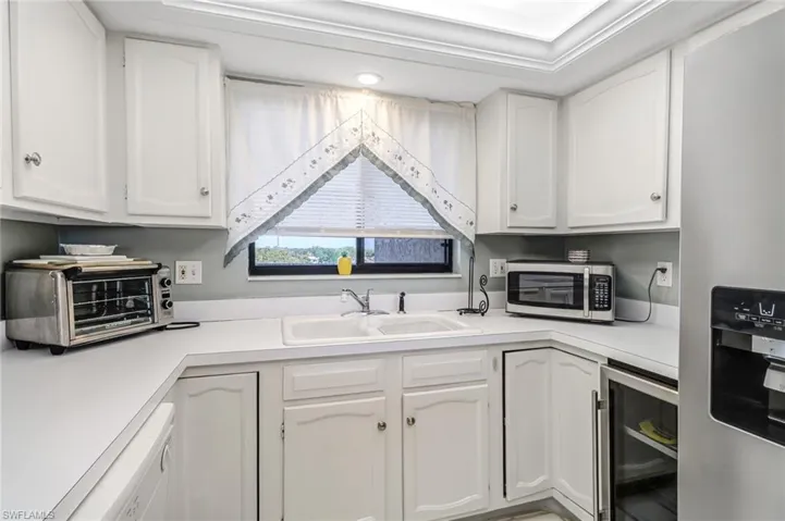 Kitchen featuring white cabinets, sink, stainless steel appliances, and beverage cooler