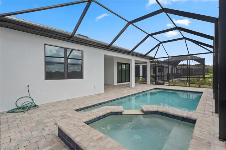 Relaxing pool / spa featuring a sunroom, a patio area, and glass enclosure