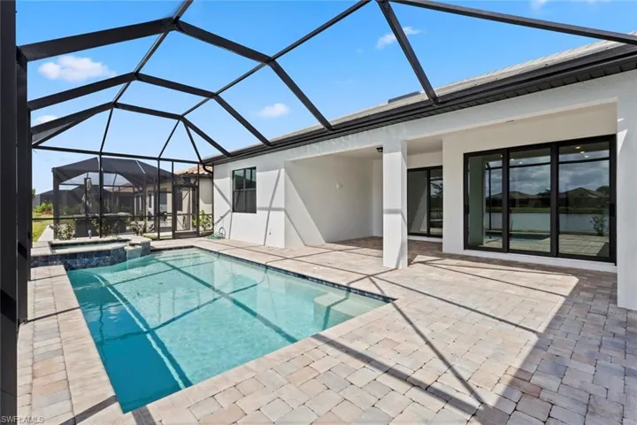 Relaxing pool / spa featuring a sunroom, a lanai, and a patio