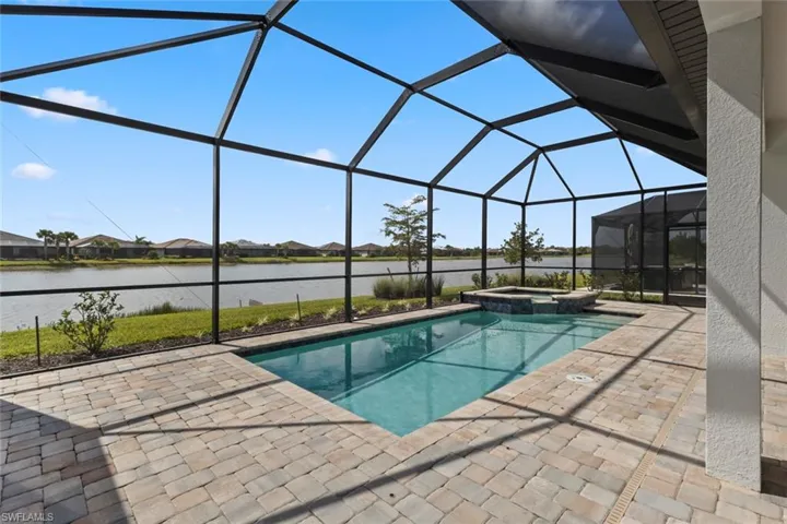 Integrated pool / hot tub featuring a sunroom, glass enclosure, a residential view, and a patio