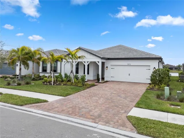 View of front of home with a garage, a front lawn, decorative driveway, and stucco siding