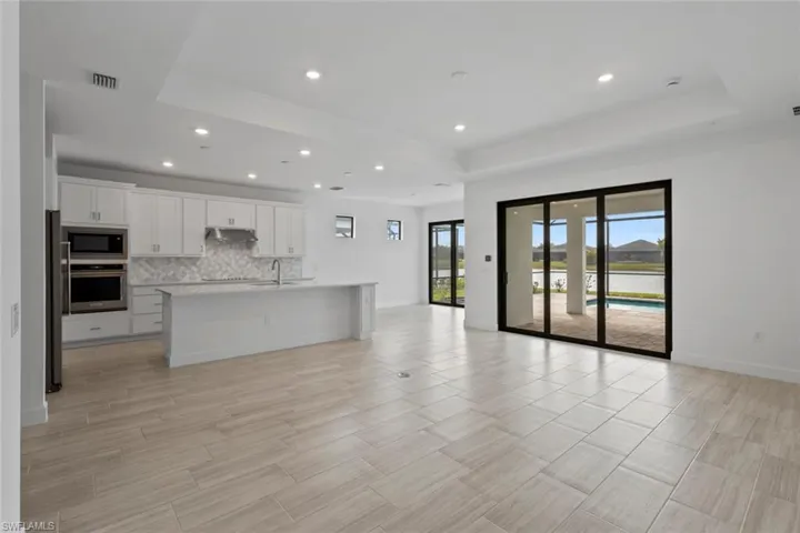 Unfurnished living room featuring a raised ceiling and recessed lighting