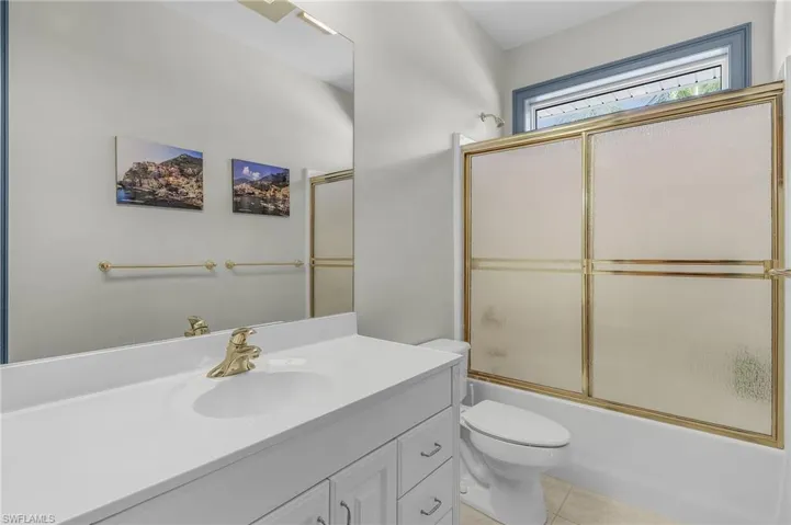 Full bath with vanity, tile patterned flooring, and enclosed tub / shower combo