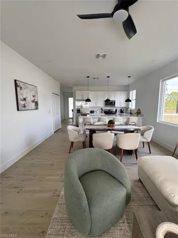Open-concept living space featuring wood-finish flooring, white walls, and a contemporary ceiling fan