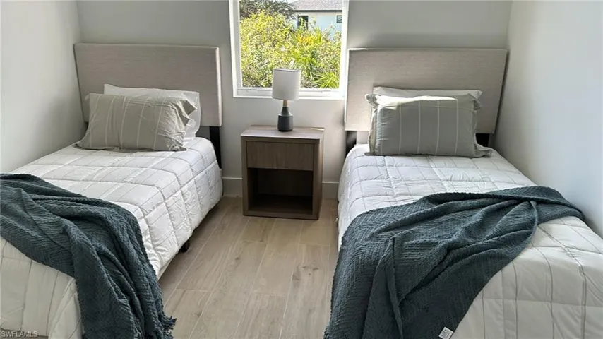 Room featuring light wood-finish flooring, white walls, and a window providing natural light