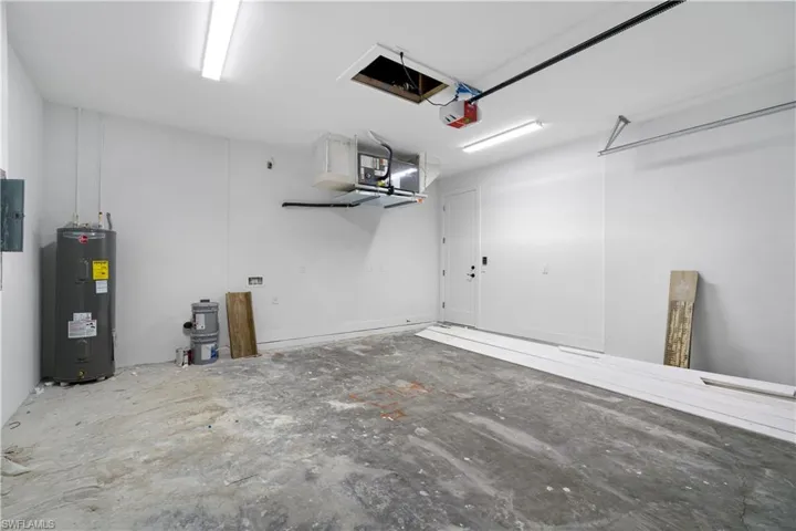 Spacious garage featuring a concrete floor, bright overhead fluorescent lighting, and a white interior door