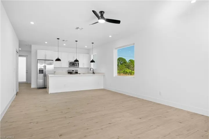 Open-concept kitchen and living area featuring wood-finish flooring, recessed lighting, and a modern ceiling fan