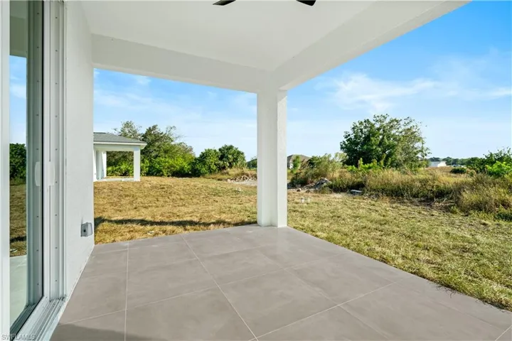 Covered outdoor patio featuring light gray large format tile flooring and a white stucco exterior wall