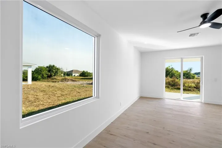 Spacious room featuring a large picture window, wood-finish flooring, a sliding glass door to the exterior, a ceiling fan with integrated lighting, and recessed lighting
