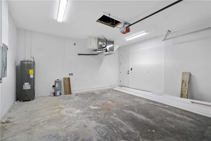 Spacious interior garage featuring a concrete floor, white painted walls, and overhead fluorescent lighting