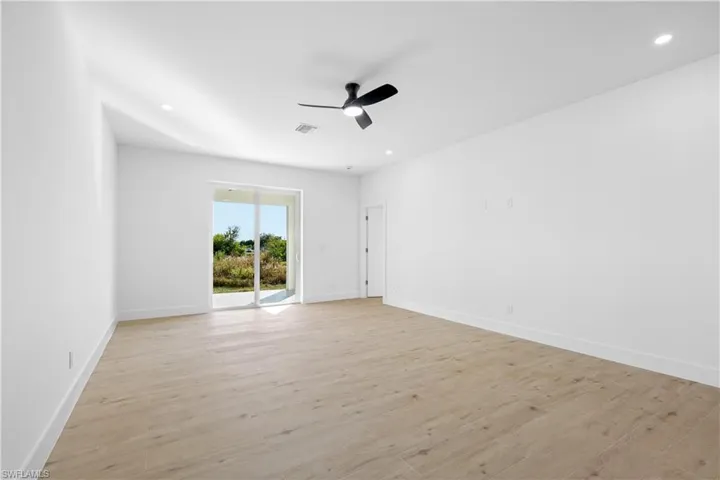 Spacious room featuring wood-finish flooring, a contemporary ceiling fan, recessed lighting, and a sliding glass door leading to the exterior