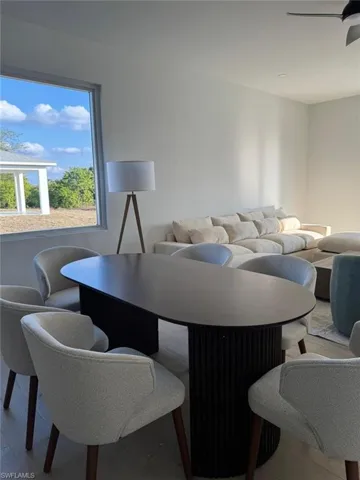 Open-concept living area featuring a prominent window, ceiling fan, and light wood-finish flooring