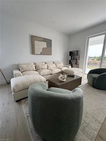 Living area featuring light wood-finish flooring and a light-toned area rug