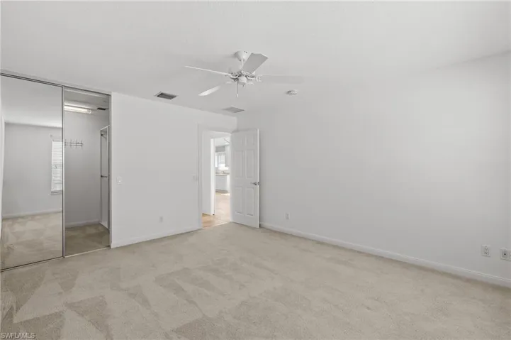 Unfurnished bedroom featuring ceiling fan, light colored carpet, and a closet