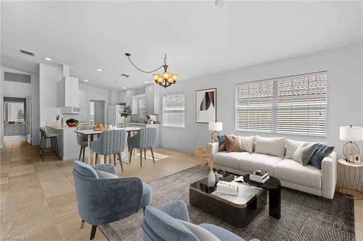 Living room with a notable chandelier, light tile patterned floors, and vaulted ceiling