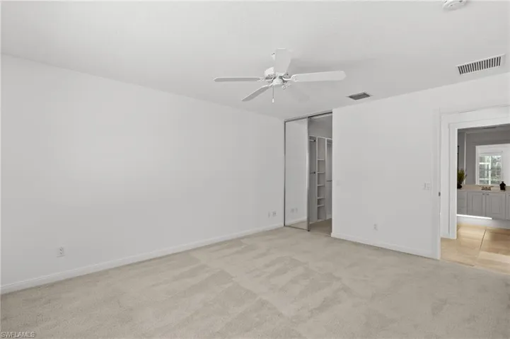Unfurnished bedroom with light colored carpet, a textured ceiling, ceiling fan, and a closet