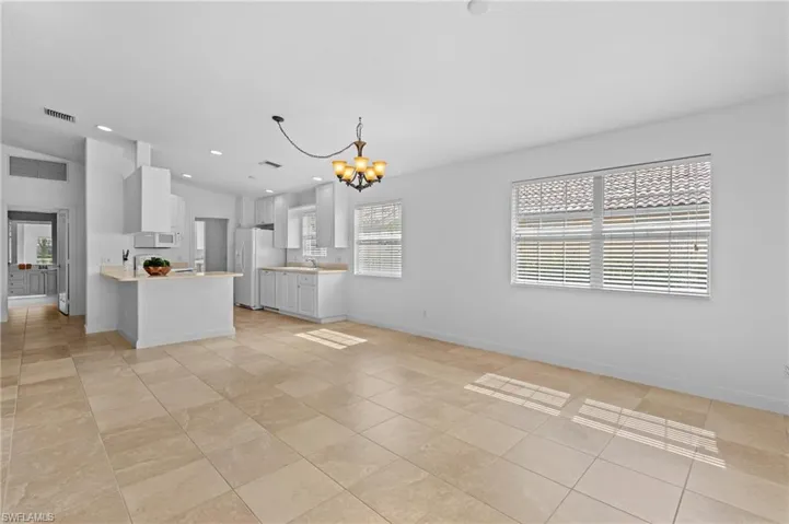 Kitchen featuring pendant lighting, white appliances, white cabinetry, a notable chandelier, and kitchen peninsula