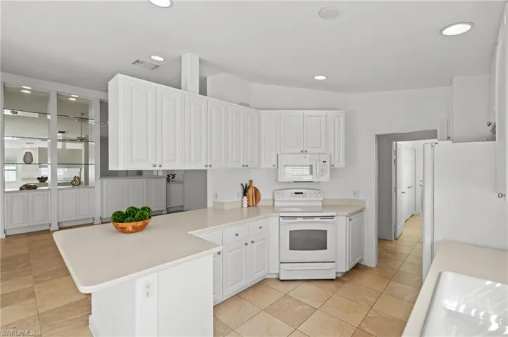 Kitchen with white cabinetry, sink, white appliances, and light tile patterned floors