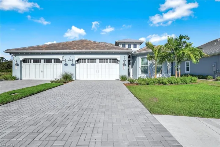 View of front facade with stucco siding, decorative driveway, a front lawn, and a garage