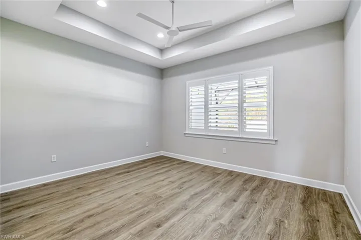 Spare room featuring a tray ceiling, wood finished floors, ceiling fan, and recessed lighting