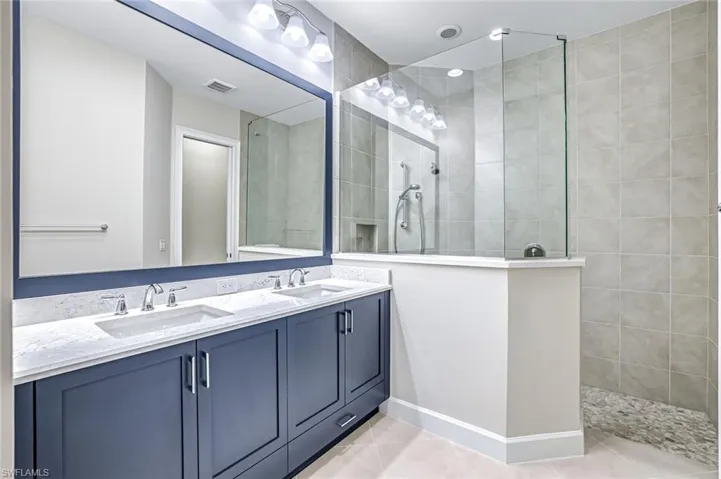 Full bathroom with double vanity, walk in shower, and light tile patterned floors