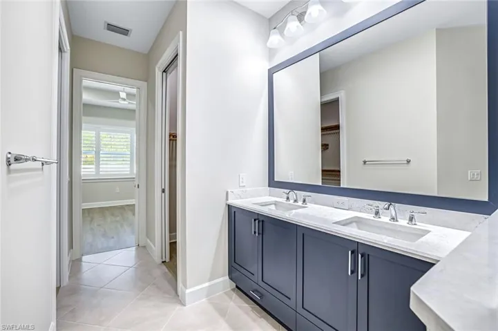 Bathroom with double vanity and light tile patterned floors