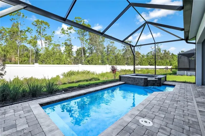 View of swimming pool with a sunroom, glass enclosure, a patio area, a pool with connected hot tub, and a fenced backyard