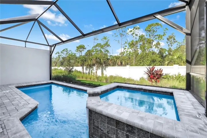View of pool with a sunroom, glass enclosure, a patio, a pool with connected hot tub, and a fenced backyard