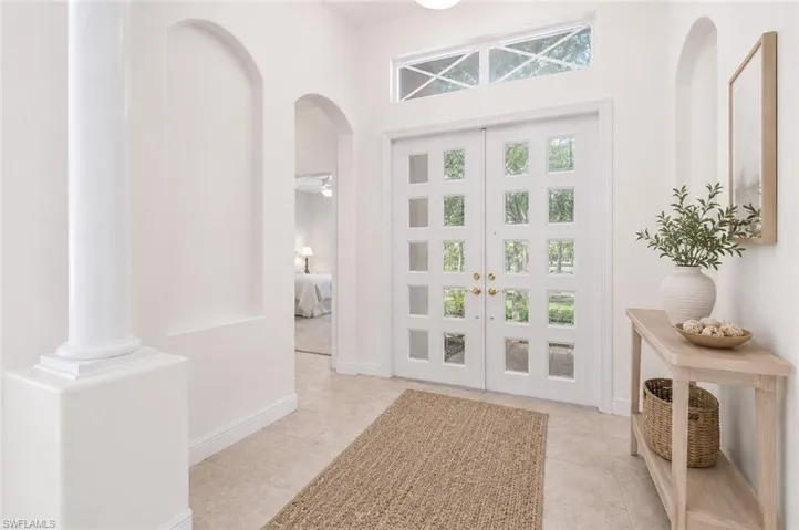 Photo shows home reimagined with white paint on walls, updated front doors and updated furnishings.  AI GENERATED