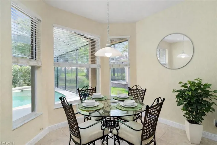Large windows in the breakfast room offer views of the pool and golf course beyond