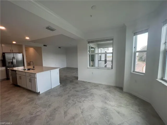 Kitchen featuring stainless steel appliances, a sink, open floor plan, baseboards, and an island with sink