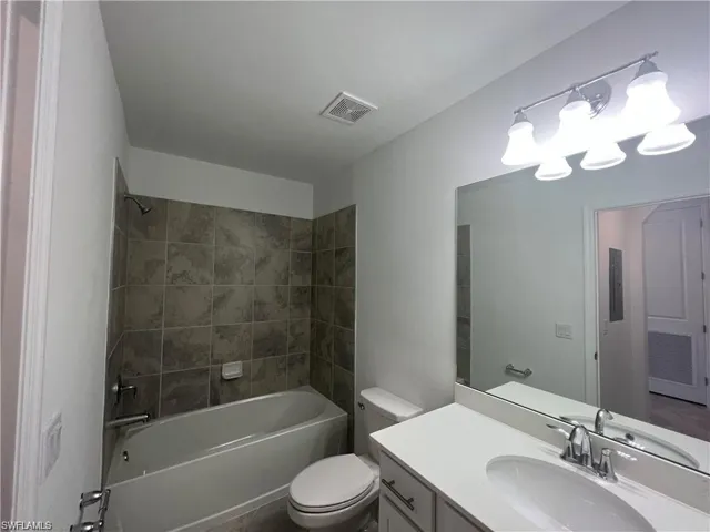 Bathroom with toilet, vanity, and tub / shower combination