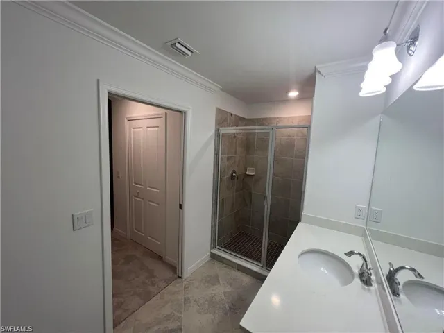 Full bathroom featuring a stall shower, vanity, tile patterned flooring, baseboards, and crown molding
