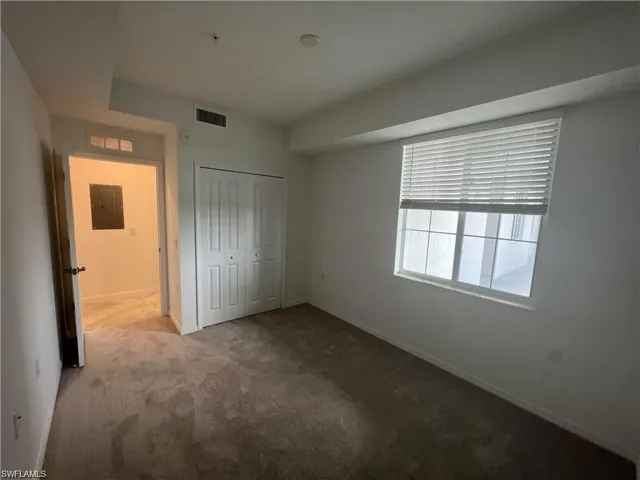 Unfurnished bedroom with electric panel, carpet flooring, a closet, and baseboards