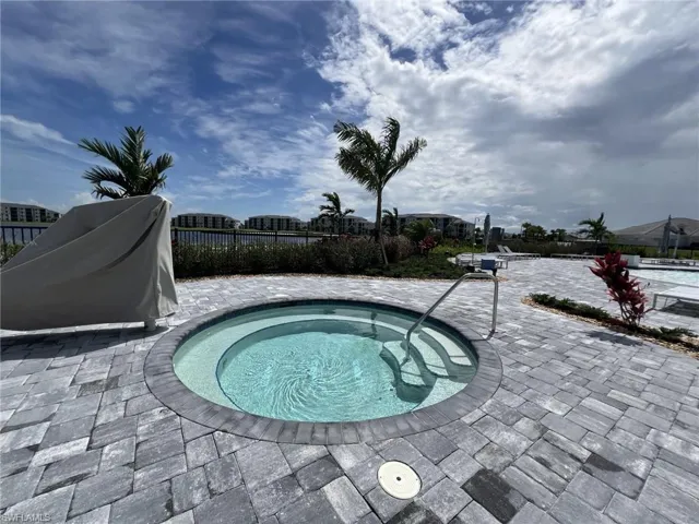 View of jacuzzi with fence, a community hot tub, and a patio area
