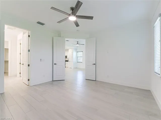 Unfurnished bedroom featuring light wood-style floors, ceiling fan, and a walk in closet