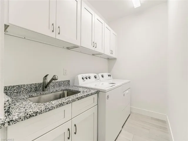 Laundry room featuring washing machine and dryer, sink, cabinet space, and light wood finished floors