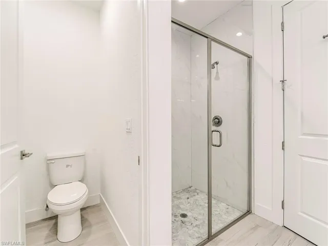 Full bath featuring light wood-type flooring and a marble finish shower