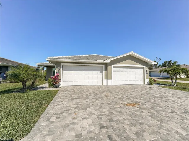 View of front facade featuring a front yard, driveway, stucco siding, and a garage