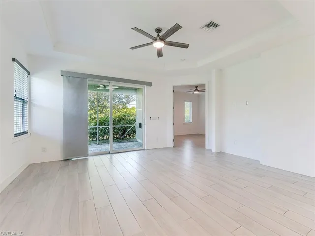 Spare room featuring a tray ceiling, light wood-style floors, and ceiling fan