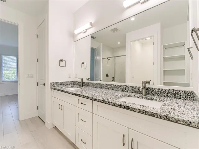 Full bathroom with a marble finish shower, double vanity, and a walk in closet