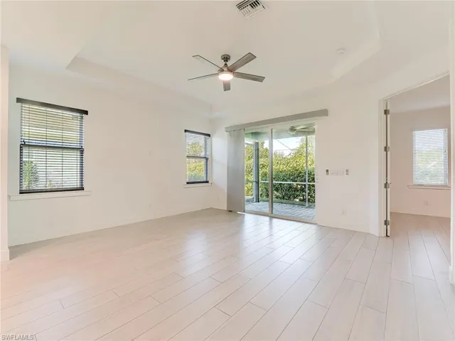 Empty room featuring a raised ceiling, wood finish floors, and ceiling fan